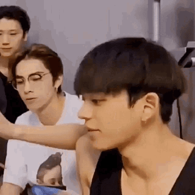 a group of young men are sitting next to each other in a room . one of the men is wearing glasses .