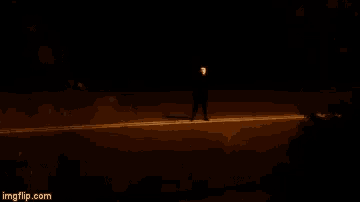 a man in a mask is standing on a street at night .