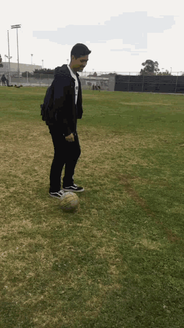 a man with a backpack is kicking a soccer ball
