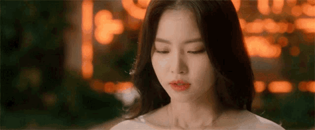 a close up of a woman 's face with her eyes closed in front of a blurry background .