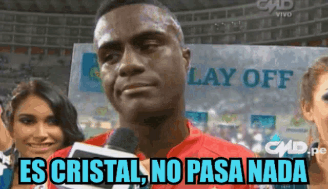 a man in a red shirt is talking into a microphone with the words es cristal no pasa nada below him