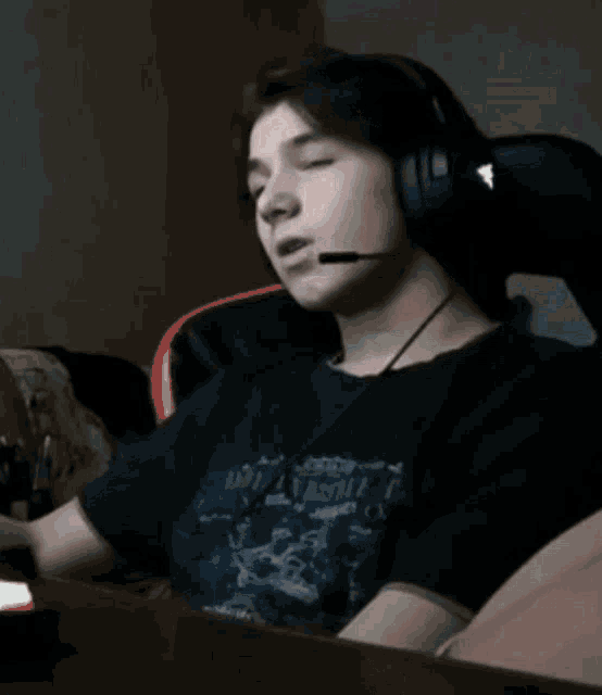 a young boy wearing headphones and a microphone is smiling while sitting at a table .