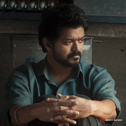 a man sits with his hands folded in front of a sony music ad