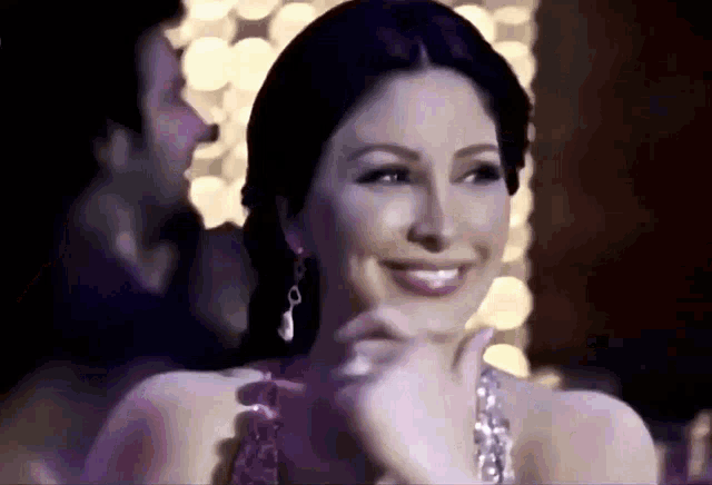 a woman in a purple dress is smiling while sitting in a dark room .