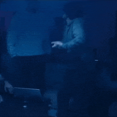 a group of people are dancing in a dark room with a laptop .