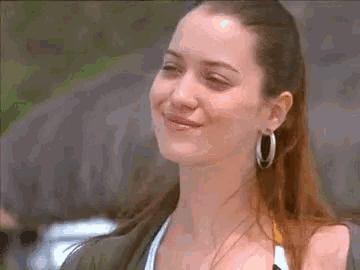 a woman wearing hoop earrings and a bikini top is smiling