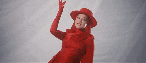 a woman in a red hat and gloves is giving the peace sign