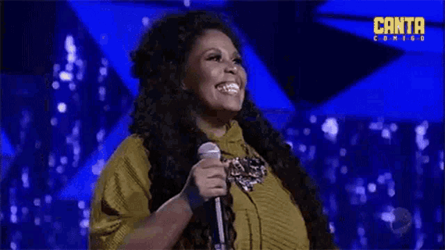 a woman is holding a microphone and smiling while standing on a stage .