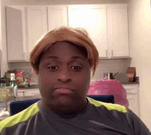 a man wearing a wig is making a funny face in a kitchen