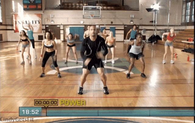 a group of people are doing exercises in a gym with a sign that says insanity