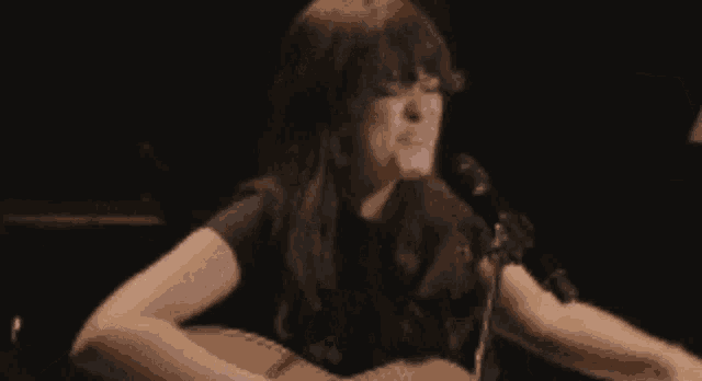 a woman is crying in front of a lamp in a dark room
