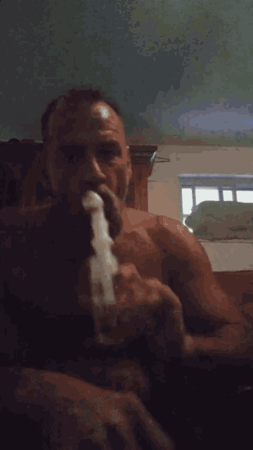 a shirtless man is smoking a pipe with smoke coming out of it