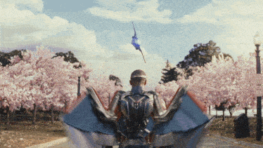 a man in a superhero costume flies a kite in a park