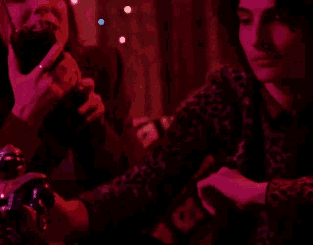 a man and a woman are playing a video game in a dark room with christmas lights in the background .