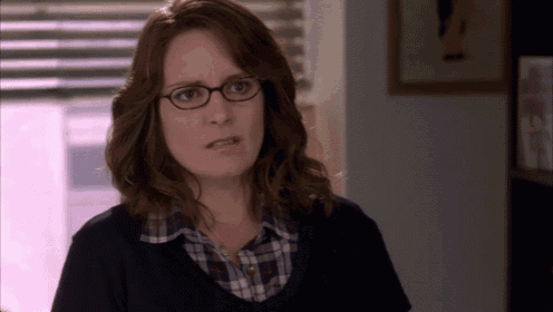a woman wearing glasses and a plaid shirt is making a face