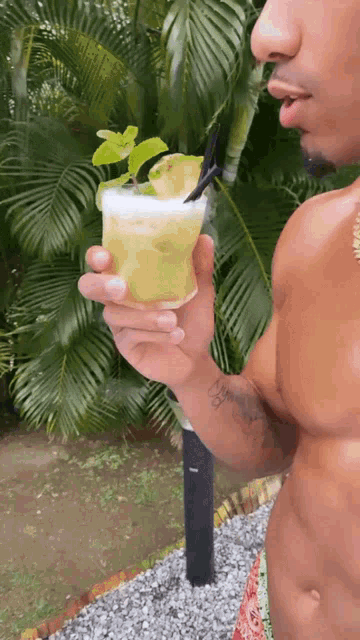 a man with a tattoo on his arm holds a drink with a straw