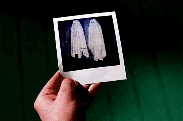 a person is holding a photo of two ghosts