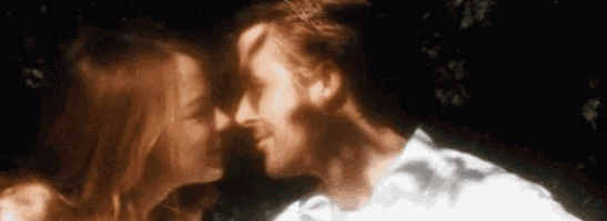 a man and a woman are kissing each other in front of a tree .
