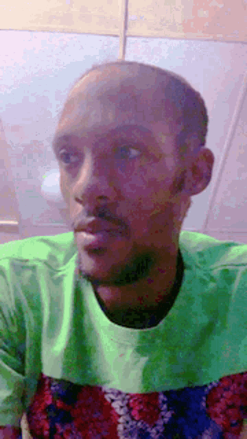 a man with a beard is wearing a green shirt and looking at the camera .