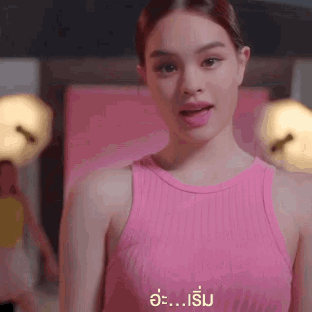 a woman in a pink tank top is making a funny face while standing in front of a mirror .