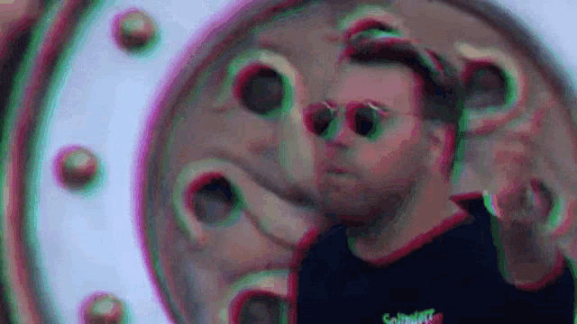 a man wearing sunglasses is standing in front of a round object .