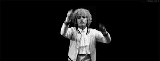 a black and white photo of a man with curly hair holding a baton .