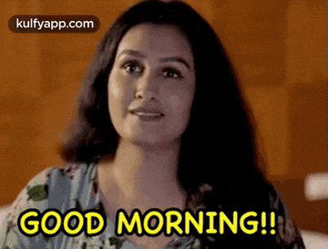 a woman is sitting on a bed and says `` good morning '' .