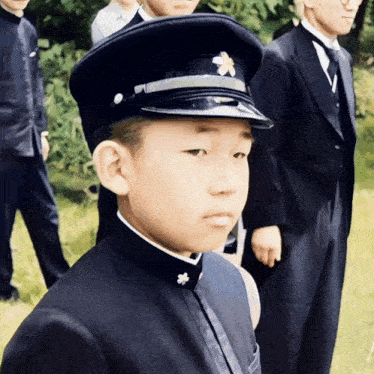 a boy wearing a hat with a flower on it stands in a crowd