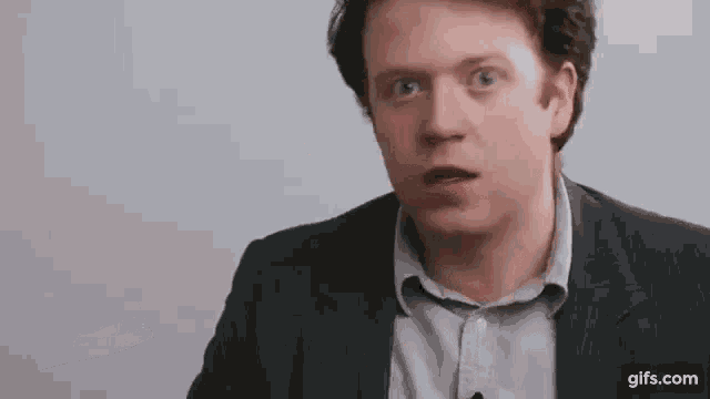 a man in a suit is making a funny face .