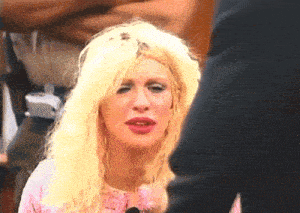 a woman with blonde hair and red lips is talking to a man in a suit