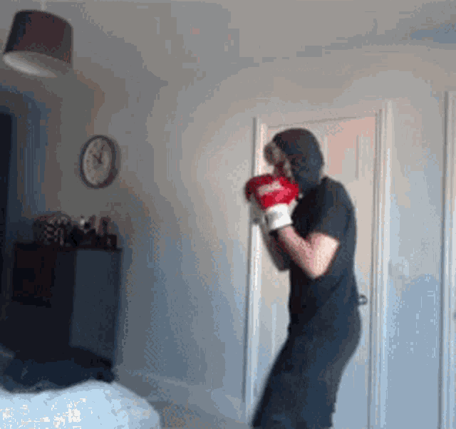 a person wearing boxing gloves in a room with a clock on the wall behind them