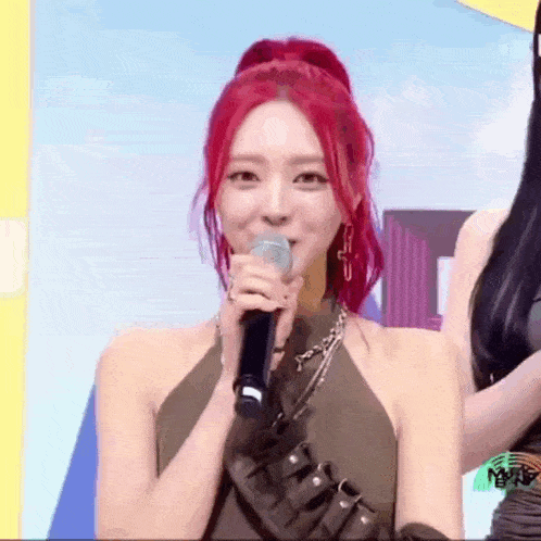 a woman with red hair is holding a microphone and smiling while standing on a stage .