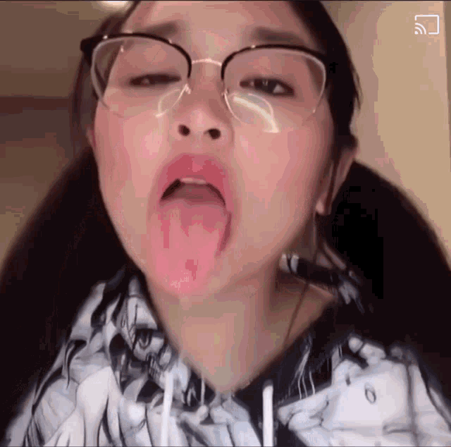a girl wearing glasses is sticking her tongue out in a video