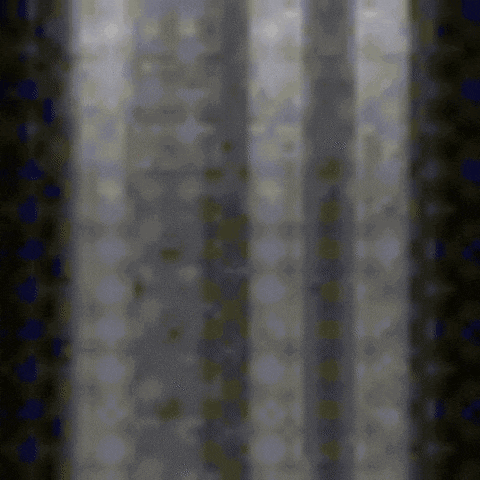 a blurred image of a dark room with a few lights coming through the curtains
