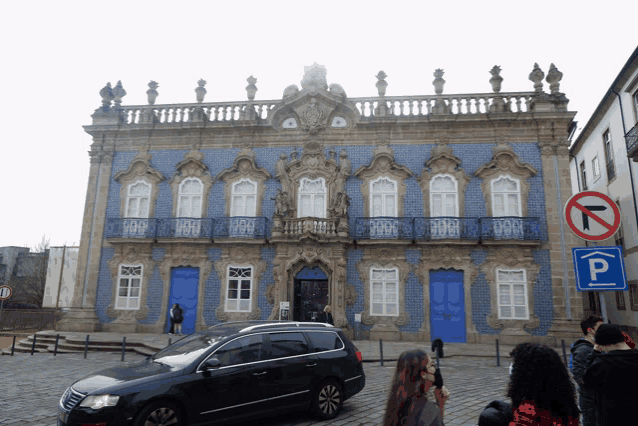 a black car is parked in front of a building with a blue door