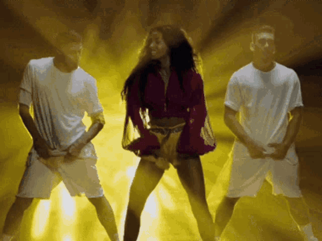 a woman in a pink top is dancing with two men in white shorts