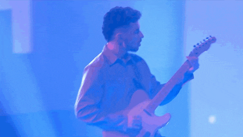a man is playing an electric guitar in a blue room