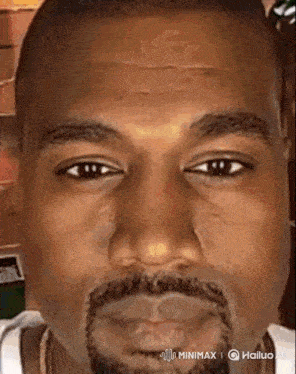 a close up of kanye west 's face with a beard and a white shirt .