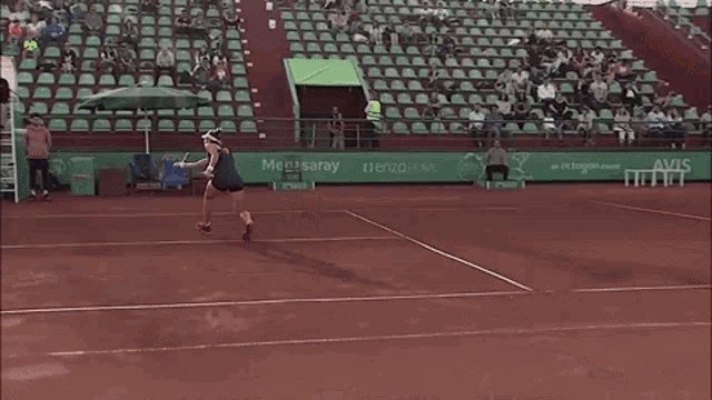 a woman is playing tennis on a court with a med saray banner in the background