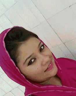 a woman wearing a pink scarf around her head is smiling