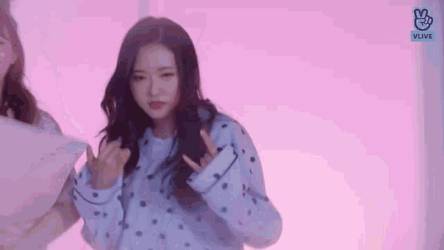 a woman in a blue and white polka dot sweater is giving the middle finger .