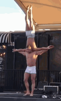 a man and a woman are doing a handstand in front of a building with the number 1140 on it