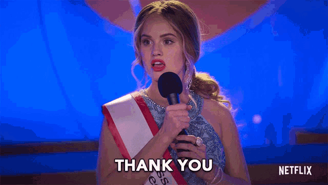 a woman holding a microphone with the words thank you on the bottom