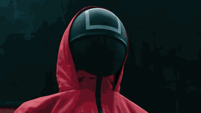 a person wearing a red hooded jacket and a black mask with a square on it