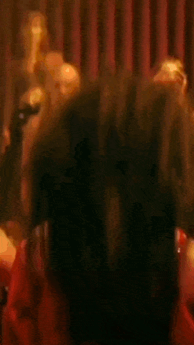 a woman in a red dress with a large breast is dancing in a dark room .