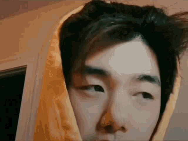 a close up of a young man wearing a yellow hoodie .
