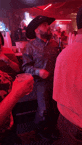 a man wearing a cowboy hat is dancing in a crowded bar