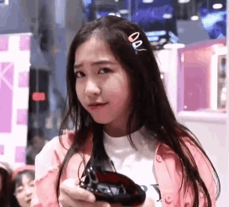 a girl in a pink jacket is holding a purse in her hand .