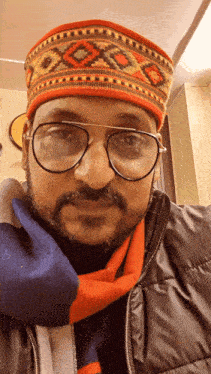 a man wearing glasses a scarf and a hat with a pattern