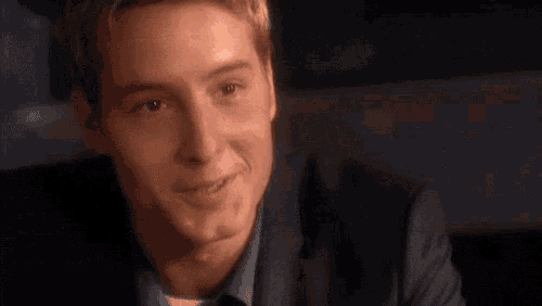 a man in a suit is smiling and looking at the camera